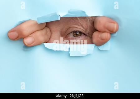 woman looking through a hole made in a poster board with her hands Stock Photo