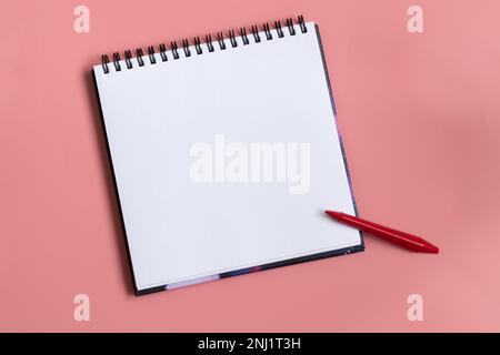 Mock up of empty scketchbook white paper on pastel pink background. One red wax crayon. Top view of open notebook with clean sheet. Copy space. Stock Photo