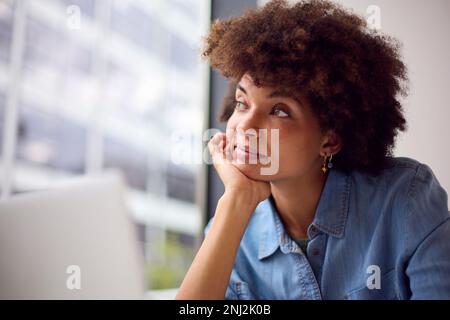 Thoughtful Young Businesswoman In Modern Office Working On Laptop Using Wireless Headset Stock Photo