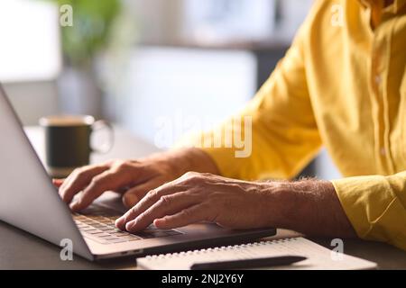 Close Up Of Man Typing On Laptop Keyboard Sitting At Desk Stock Photo