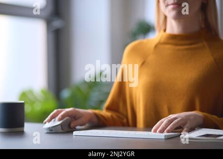 Close Up Of Woman Typing On Computer Keyboard Sitting At Desk Stock Photo