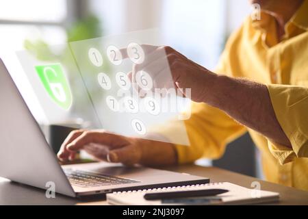 Online Security Concept With Man Using Laptop With Graphic Overlay Of Lock And PIN Number Keypad Stock Photo