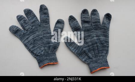 two fabric work gloves made of gray-black material isolated on a light surface, protective cotton gloves intended for manual work close-up Stock Photo
