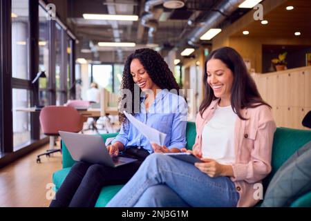 Two Businesswomen Having Informal Meeting In Breakout Seating Area Of Modern Office Stock Photo