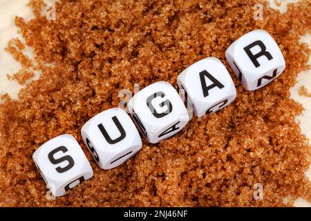 Sugar written in letter dice on brown sugar Stock Photo