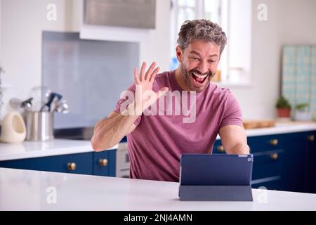 Portrait Of Mature Man Using Digital Tablet At Home To Make Video Call Stock Photo