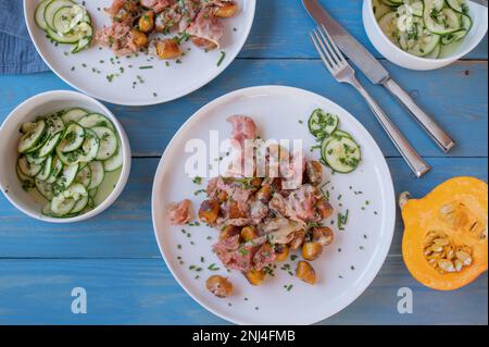 Pan fried pumpkin gnocchi with ham, cheese and herbs on blue wooden background Stock Photo