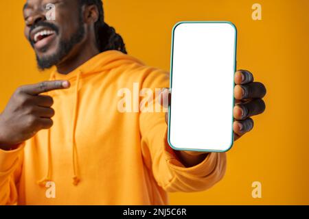 Smiling african man pointing at cellphone with blank screen with copy space Stock Photo