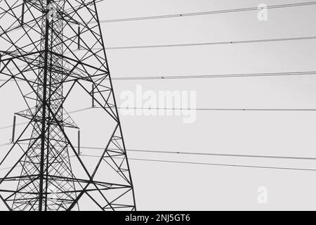 Overhead power line pylons and electrical cable wires sihouette. Black and white. Stock Photo