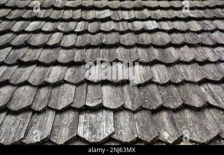 Gray, wooden roof tiles background, texture. A close-up of an old gray roof covered with wooden tiles. Stock Photo