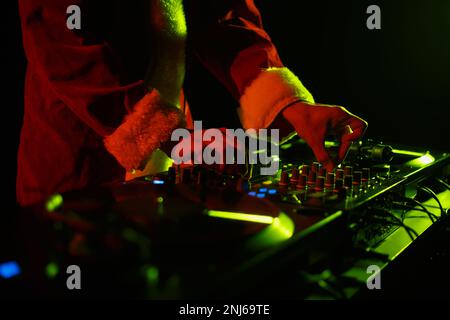 Christmas party DJ plays music. Santa Claus disc jockey mixing musical tracks in night club Stock Photo