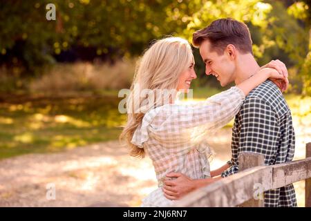 Loving Young Couple Leaning On Fence On Walk In Countryside Together Stock Photo