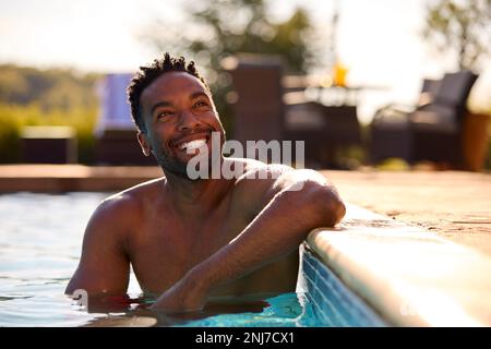 Smiling Man On Summer Holiday Relaxing In Swimming Pool Stock Photo