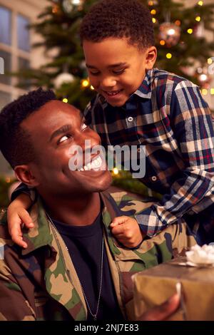 American Soldier In Uniform Home On Leave For Christmas Giving Son Present Stock Photo