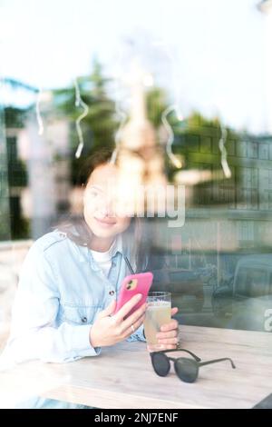 Woman sitting into the cafe smiling and looking outside through the window.x Stock Photo