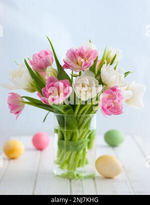 Easter bouquet of spring tulips and Easter eggs on white wooden table. Easter concept with copy space. Stock Photo
