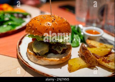 Healthy food, organic vegetarian burger with plant based falafel balls, vegan cheese, green lettuce and baked potatoes Stock Photo