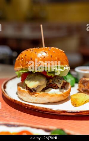 Healthy food, organic vegetarian burger with plant based falafel balls, vegan cheese, green lettuce and baked potatoes Stock Photo