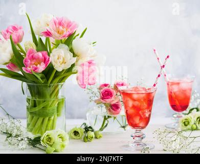 Refreshing summer drink with strawberry in  glasses and flowers in vase on wooden table Stock Photo