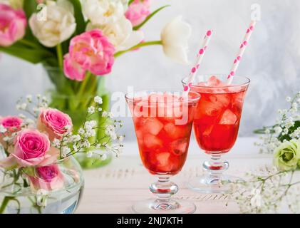 Refreshing summer drink with strawberry in  glasses and flowers in vase on wooden table Stock Photo