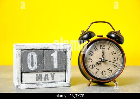 May 1, calendar and old retro alarm clock on a yellow background Stock Photo