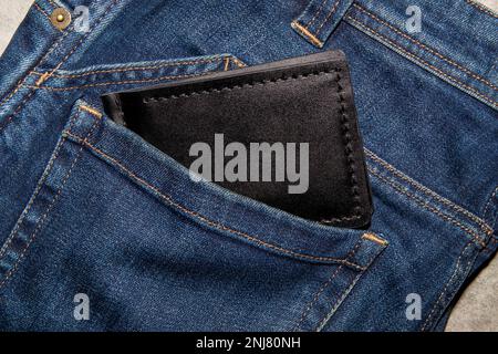 Black handmade leather wallet on blue jeans. Male background. View from above. Stock Photo