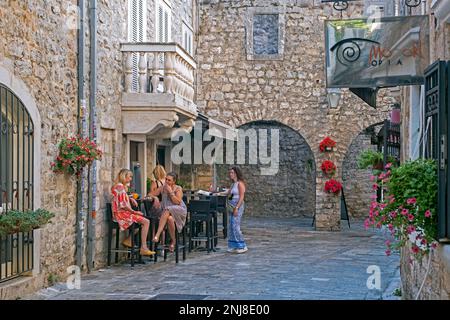 Montenegrin locals having a drink outside café in the medieval Old Town centre of the city Budva along the Adriatic Sea, Montenegro Stock Photo