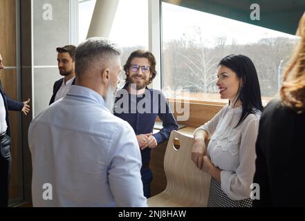 Cheerful business people enjoy socializing and discussing during work break in office. Stock Photo