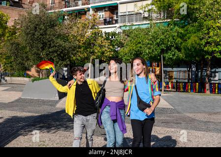Young diverse friends walking on the street with the lgbt rainbow flag. Stock Photo