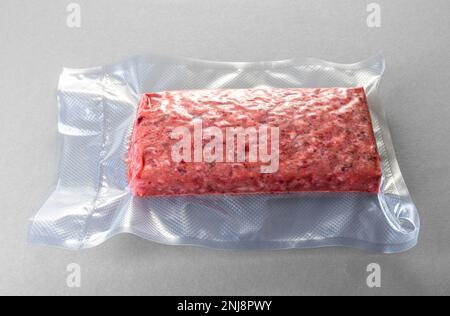 Raw minced meat roll in vacuum pack for sous vide cooking on gray background Stock Photo