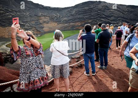 tourists take photos at the viewing spot above the green lake at el golfo Lanzarote, Canary Islands, Spain Stock Photo