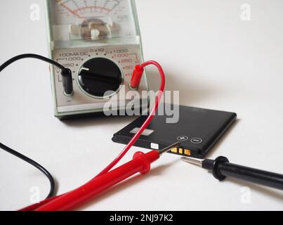 Battery condition test with voltmeter on a white background. Stock Photo
