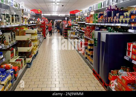 Inside supermarket with aisle full of mixed food items and customers Stock Photo