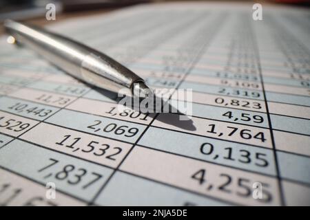 A gray metal pen lies on a table with numbers, close-up Stock Photo