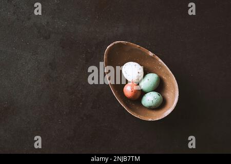 Cracked easter chocolate egg  full with small chocolate eggs on black background Stock Photo