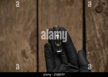 hand in gloves holds an ampoule with medicine Stock Photo