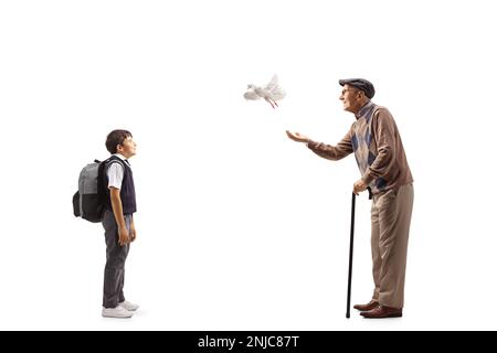 Full length profile shot of a schoolboy watching an elderly man letting a dove fly isolated on white background Stock Photo