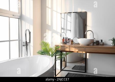 Interior of light bathroom with bathtub, table and mirror Stock Photo
