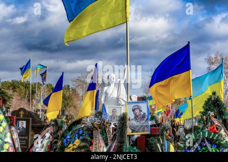 Kyiv, Kyiv Oblast, Ukraine. 21st Feb, 2023. Blue and yellow Ukrainian national flags are blown by the wind and flowers lie on graves of soldiers killed in combat against Russian forces, at the Lisove cemetery in the capital of Ukraine. As the full scale invasion of Ukraine by the Russian forces approaches its first anniversary the casualty rate is very hight, though the exact numbers are unknown. A minimum of 13 thousand Ukrainian soldiers have lost their lives. (Credit Image: © Dominika Zarzycka/SOPA Images via ZUMA Press Wire) EDITORIAL USAGE ONLY! Not for Commercial USAGE! Stock Photo