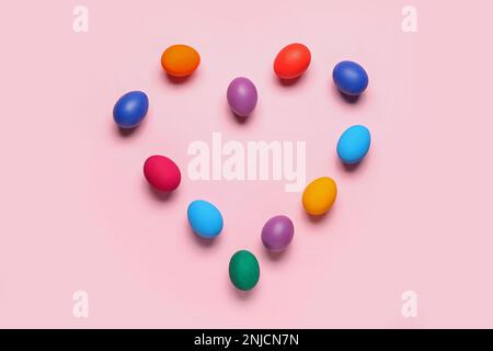 Heart made of colorful Easter eggs on pink background Stock Photo