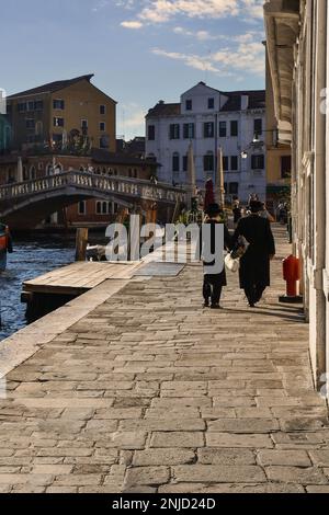 Fondamenta Venier Savorgnan waterfront on the Cannaregio Canal with rear view of orthodox jews and the Guglie Bridge in the background, Venice, Italy Stock Photo