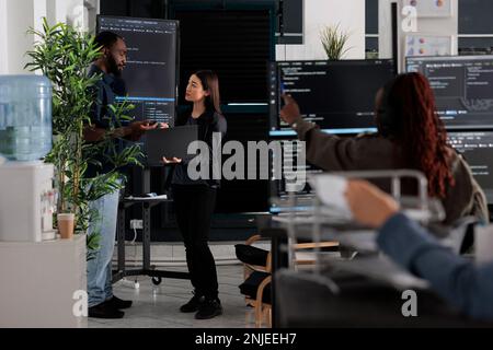 Software engineers discussing about algorithms on big screen and laptop, analyzing html script language. Team of system programmers discussing database on terminal window, server interface. Stock Photo