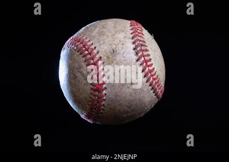 Old rough baseball with dramatic lighting isolated on a black background Stock Photo