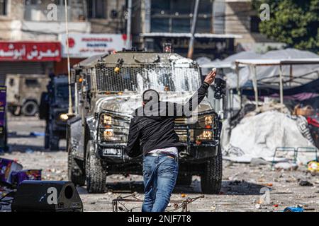 Nablus, Palestine. 22nd Feb, 2023. Palestinian youths throw goods and vegetables at the vehicles of the Israeli army during the clashes at the vegetable market in the old city of Nablus in the occupied West Bank. Clashes broke up between Palestinians and Israeli army after the Israeli army broke into the shelter in which Palestinian gunmen from the Lions' Den groups were hiding in the old town of Nablus, killing four gunmen and six civilians who were present at the market during the raid. Credit: SOPA Images Limited/Alamy Live News Stock Photo