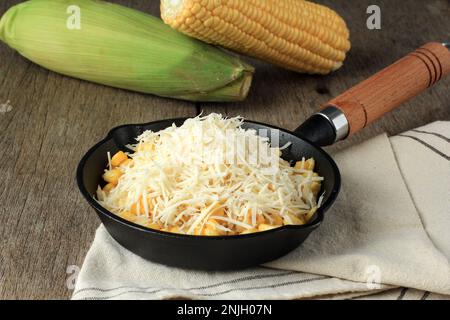 Creamy Corn with Cream and Grated Cheese on Cast Iron Skillet Stock Photo