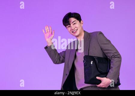 handsome Korean young man leaving work on time with briefcase Stock Photo