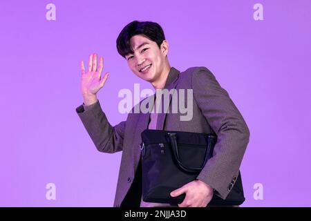 handsome Korean young man leaving work on time with briefcase Stock Photo