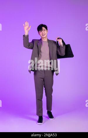 handsome Korean young man leaving work on time with briefcase Stock Photo