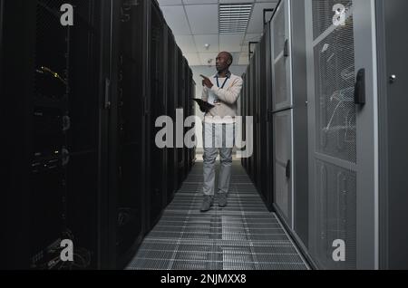 Technician, cybersecurity and man in the server room for data maintenance, it or analysis. System, engineer and African male coder or programmer doing Stock Photo