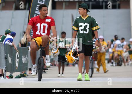 ASHWAUBENON, WI - JULY 27: Green Bay Packers linebacker Isaiah McDuffie  (58) bikes with a fan during Green Bay Packers training camp at Ray  Nitschke Field on July 27, 2022 in Ashwaubanon